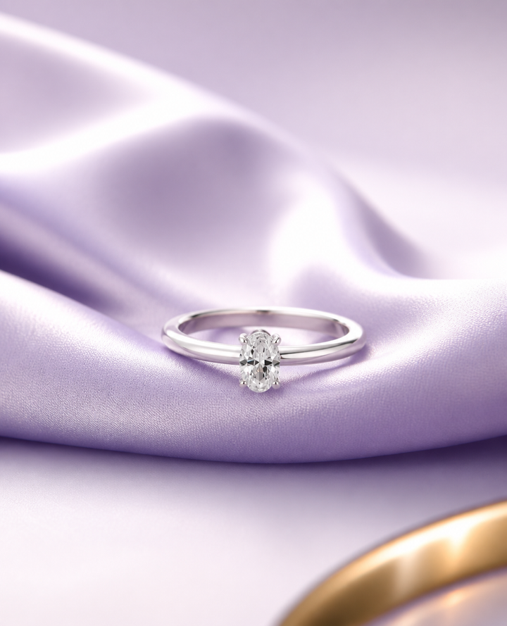 white gold ring with a diamond on a purple satin background